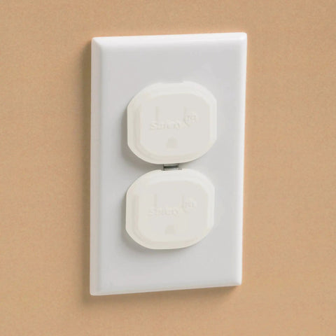 Close-up of white electrical outlet with two removable, reusable covers sealing live sockets to keep curious hands safe