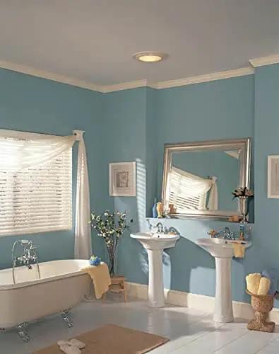 Round White Bath Exhaust Fan With Light And Glass Lens, 100 CFM, installed in a bathroom ceiling, showcasing modern look and easy install.