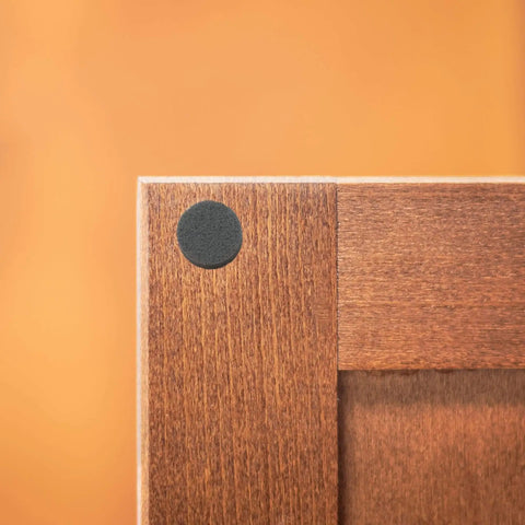 Assorted Round Self Stick Noise Dampening Foam Cabinet Bumper in use on wooden cabinet for quiet closures and surface protection.