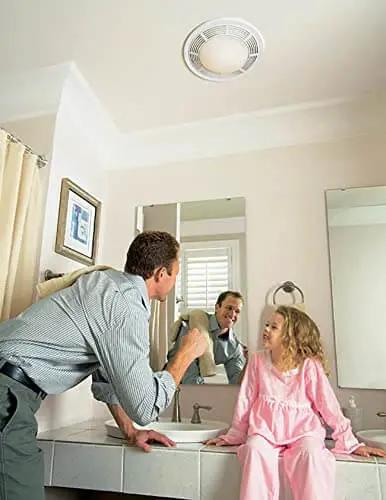 Installed Round White Bath Exhaust Fan With Light And Glass Lens, 100 CFM, 3.5 Sones, 4 Inch Duct, 100 Watt Light in bathroom ceiling.