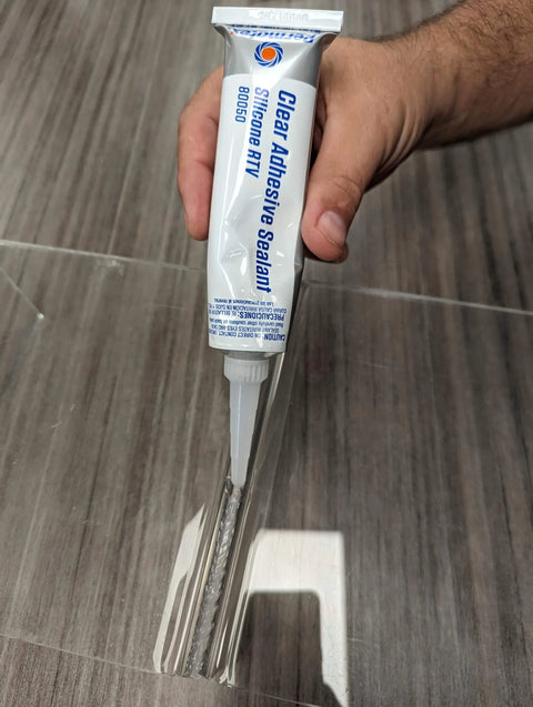 Clear RTV Silicone Adhesive Sealant 3 Oz Sensor Safe General Purpose Sealant For Inside Or Outside Use That Bonds Seals Repairs Glass Metal Plastic Vinyl Fabric Weather Stripping And More For Quick Fixes being applied to a surface.