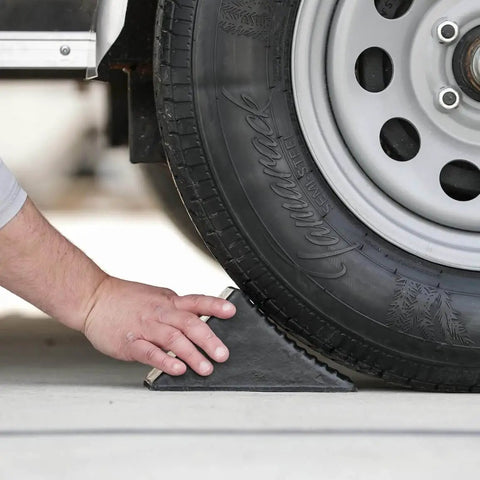 Hand placing Beefy Rubber Wheel Chock For Cars Trailers RVs And Utility Vehicles With Reinforced Grip Weather And Chemical Resistant 5x6x5 Inch under tire