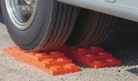 Interlocking RV Leveling Blocks 10 Pack With Nylon Storage Bag For Trailer Motorhome And Vanlife Up To 40,000 Lbs Capacity Orange Made In USA By Tri-Lynx Lynx Levelers under a vehicle tire on gravel