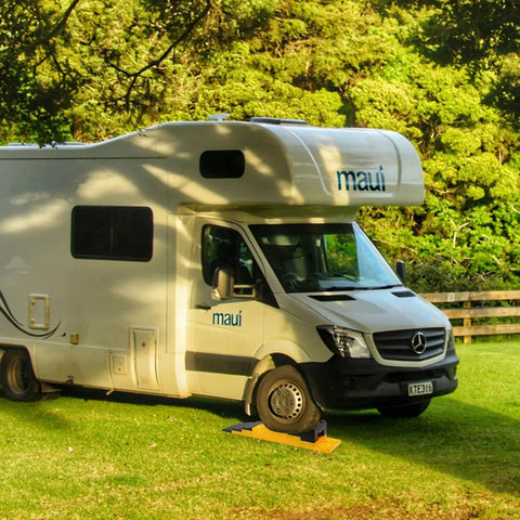 RV Camper on grass with RV Camper Leveling Blocks Set With Anti Slip Pads Interlocking Design 10 Pack Includes One Wheel Chock Ramps.