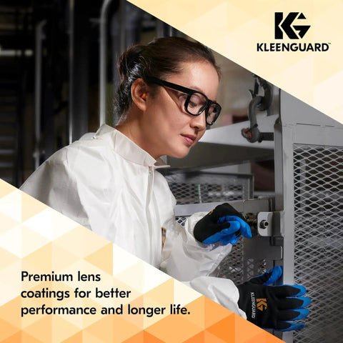 Worker wearing eyewear and gloves operating machinery in a workshop setting.