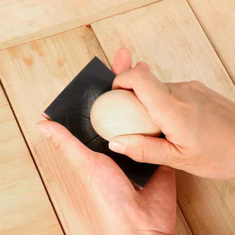 Hand using 24 Pcs Sanding Sponges 800 1000 Grit Reusable Blocks for Wood Metal Drywall on a wooden surface