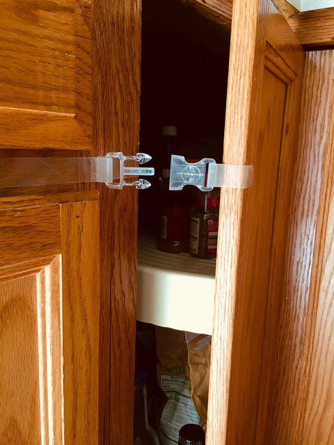 Self Adhesive Safety Latches For Baby And Adults securing a cabinet door, clear 9-inch strap, four flaps, installed with no tools.