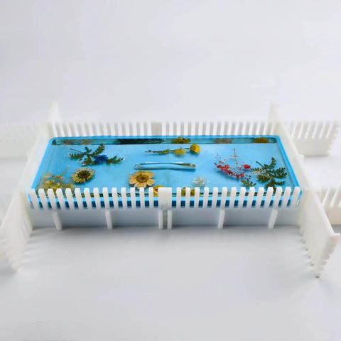 Adjustable Silicone Resin Mold Border Brackets 4 Pack for Mold Housing, securing a blue resin cast with flowers, side view