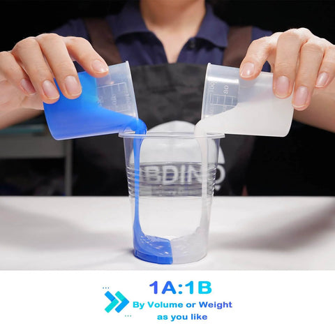 Pouring sapphire blue and white liquid silicone mold making kit into a clear container, 1:1 by volume ratio, DIY project.
