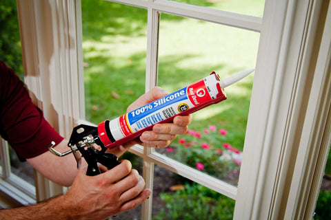 Person applying 100 Percent Silicone Architectural Grade RTV Sealant For Indoor And Outdoor Use Weather Resistant Black Caulk to window
