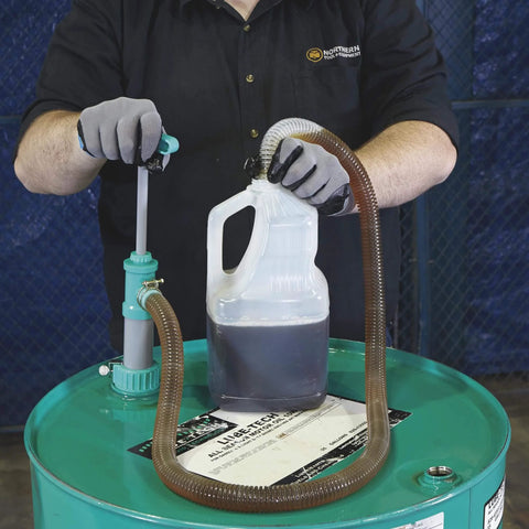 Person using Ironton Siphon Drum Pump - 7 GPM to transfer liquid from a 55-gallon drum with flexible hose into a container