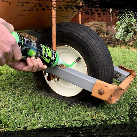 Applying Slime 10193 Tire and Tube Sealant Puncture Repair Sealant, 2-in-1, into a wheelbarrow tire outdoors.