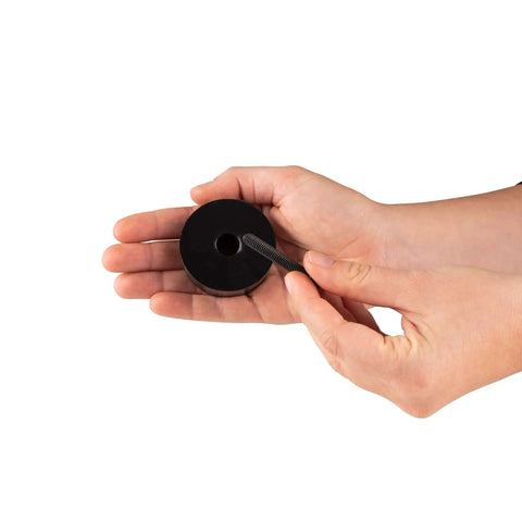 Hands holding a Sorbothane anti-vibration leveling mount with 1/4-20 threads, 2 inch stud, 2 inch diameter, 70 Duro, 2 pieces.