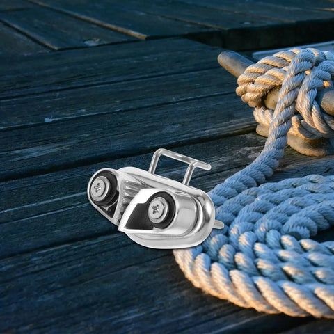 Front view of Healvian stainless steel cam cleat rope lock with ball bearing beside a coiled rope on a wooden deck