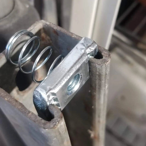 Close-up of stainless steel 3/8-16 standard strut channel nuts with a thickened spring in a slotted channel system.