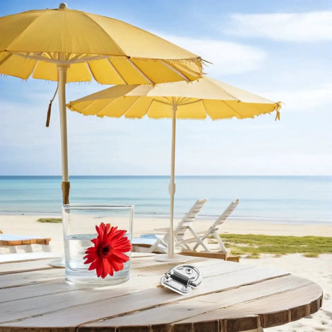 Marine-grade stainless steel folding D-ring tie-down anchor on a round wooden beach table.