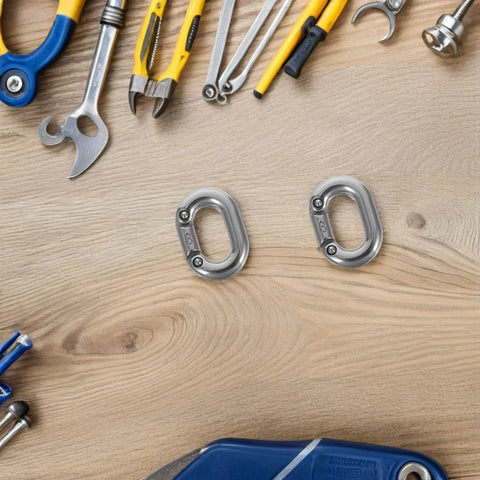 Two 8mm stainless steel oval quick links with screws, marine-grade fasteners on a wood workbench.