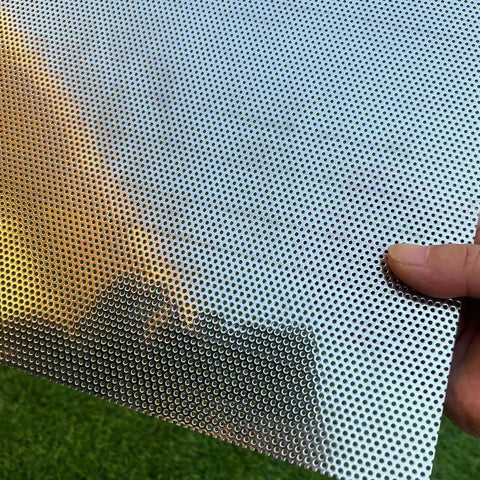 Close-up of a Stainless Steel Perforated Sheet 16x10 In, 304 Grade, 19 Gauge With 1/16 Inch Openings, held outdoors.