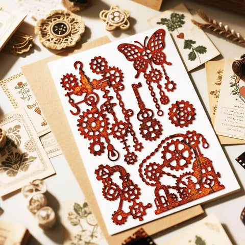 Steampunk Gear Die Cut Set For Scrapbooking And Card Making With Slick Mechanical Butterfly Embossing Stencils, Vintage Gear Frames, DIY Crafts by MAYJOYDIY displayed on a table with various decorative elements.