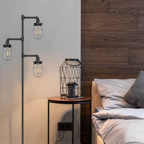 Three Head Steampunk Floor Lamp With Birdcage Shade Dope Industrial Rustic Edison Bulb Black Finish And Adjustable Cross Stand next to a bed