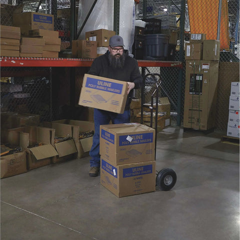 Person using a Steel Pneumatic Hand Truck Dolly - 600-Lb. Capacity, 10in. Tires, Powder-Coat Finish in a warehouse.