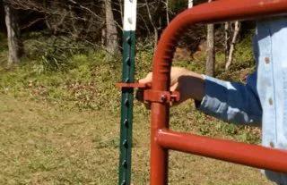 Person installing gate with Patented T Post Hinge Pins for easy gate hanging from metal T posts, showing secure connection.
