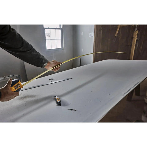 Person using Atomic Compact 30 Ft Tape Measure With Finger Brake For Precision And One Hand Quick Measurement on a workbench