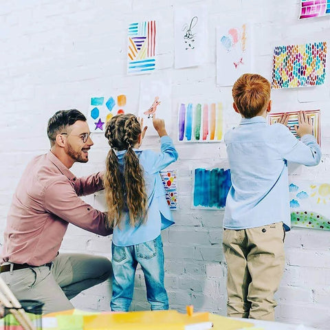 Teacher helping children hang art with Teacher Tape Pads Double Sided Removable Foam Tape For Wall Mounting 96 Pieces Per Pack
