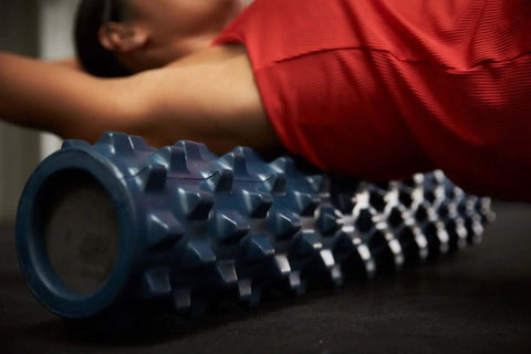 Person using 22-inch textured foam roller for deep tissue massage and self-myofascial release with firm, flexible bumps