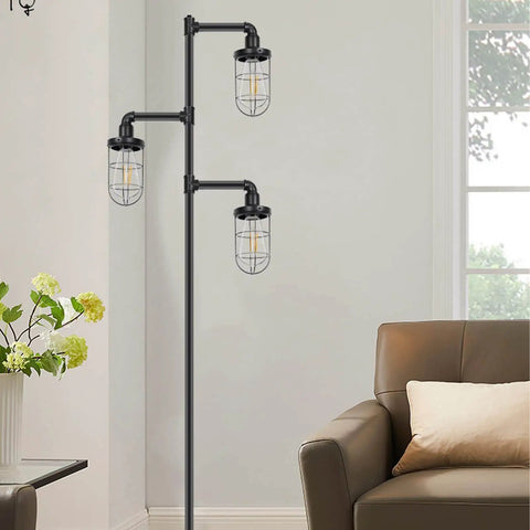 Three Head Steampunk Floor Lamp With Birdcage Shade Dope Industrial Rustic Edison Bulb Black Finish And Adjustable Cross Stand For Farmhouse Or Loft Living Room Decor By CONCA standing in a living room corner next to a chair.