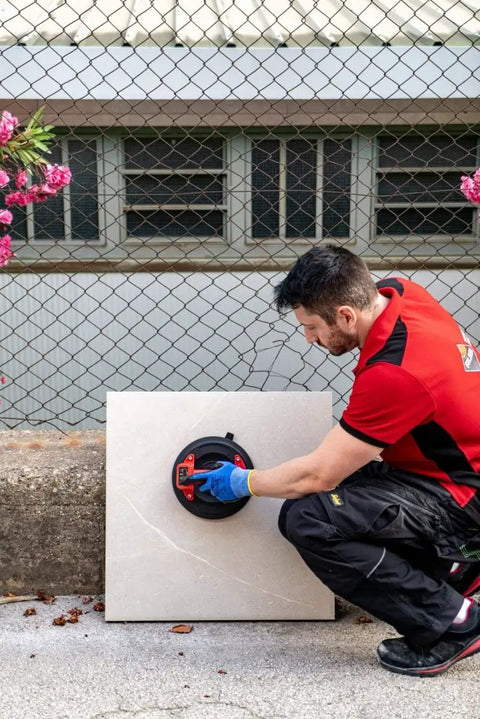 Professional using Battery Powered Tile Vacuum Suction Cup Tool for handling ceramic tiles, 220 mm grip, up to 140 kg capacity