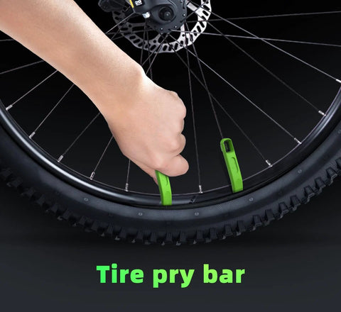 Two green MTB tire levers used to remove a 29-inch mountain bike tire from the rim.