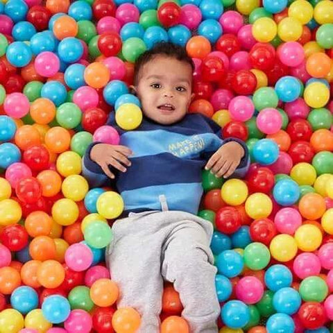Young child playing in BPA Free Crush-Proof Plastic Ball Pit Balls with Storage Bag, featuring 6 bright colors, pack of 400.