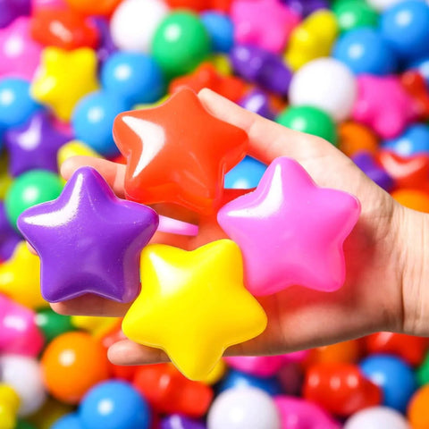 Hand holding star-shaped ball pit balls in rainbow colors. Ball Pit Balls for Toddlers - 50 Count Star Balls Different Shapes for Festival Indoor Outdoor, Party Decoration for Babies Kids (Rainbow). Non-toxic play balls.