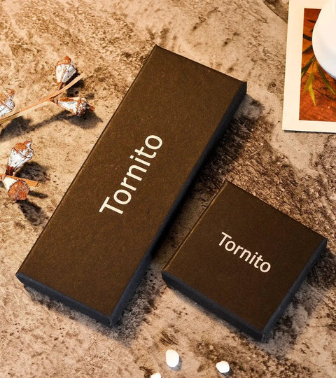 Black gift boxes displaying brand name Tornito, suitable for jewelry packaging, on a textured surface with decorative elements.