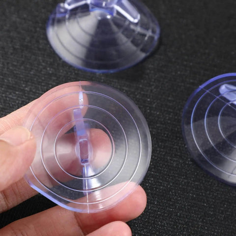 Hand holding a 45mm transparent PVC aquarium suction cup from the 12 pack for glass surfaces, showing vacuum ring design for secure mounts.
