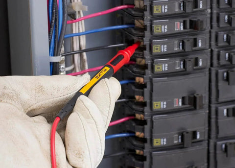 Hand using Twistguard Test Leads, 2 mm Diameter Probe Tips to test electrical panel connections, highlighting flexible use and design.
