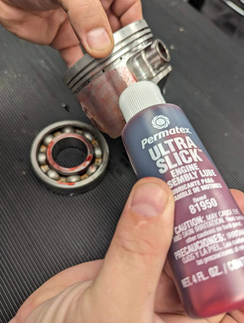 Applying Permatex 81950 Ultra Slick Engine Assembly Lube, 4 oz., Red to metal engine components.