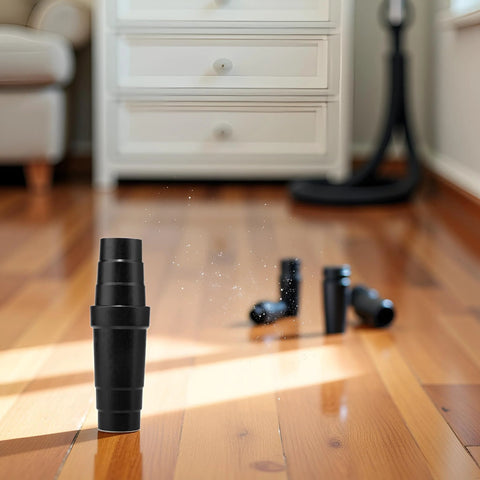 Vacuum cleaner hose adapter, black ABS universal reducer, on a wooden floor with extra parts nearby.