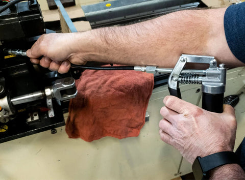 Person using LubriMatic 30-800 Heavy Duty Mini Grease Gun w/ Pipe and Hose, Black/Silver on machinery