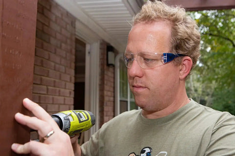 Man wearing UV Protection Safety Goggles With 99 Percent UV Impact Resistant Clear Lenses using a drill outdoors.