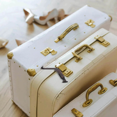 White and cream vintage suitcases with brass handles on a wooden floor, surrounded by beige high heels.