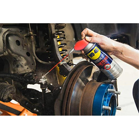 Applying WD-40 Specialist Penetrant with Smart Straw to metal threads on vehicle brake disc, 11 oz can, close-up view.