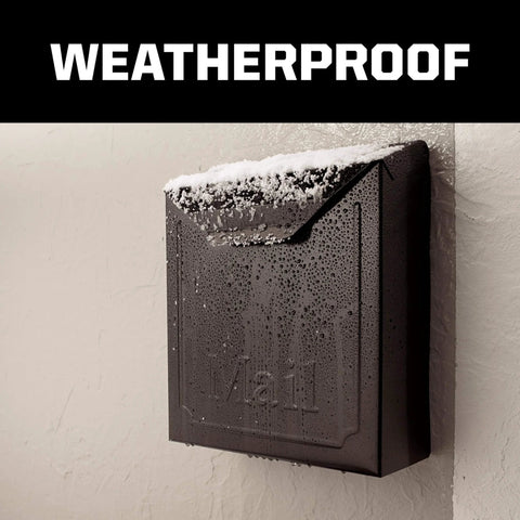 Black weatherproof mailbox mounted on a wall covered in snow and moisture droplets, demonstrating durability and resilience.