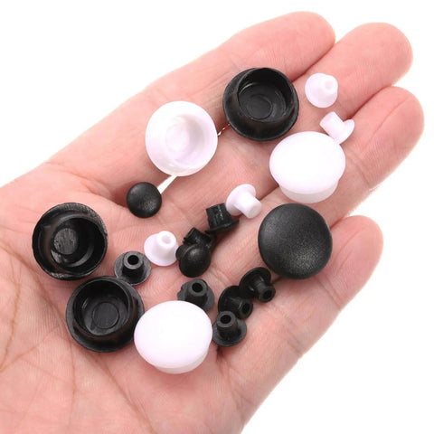 Assorted black and white plastic caps and plugs on hand for cabinets and furniture
