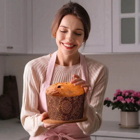 Smiling woman holding a panettone in a 48 Pack Easter Panettone Paper Mold 15 Oz Nonstick Brown Round Paska Kulich Baking Mold