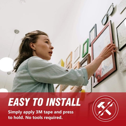 Person installing frames on wall using 3M 5925 Black Double Sided Foam Tape 0.5 Inch By 18 Feet Heavy Duty Waterproof Mounting Tape.