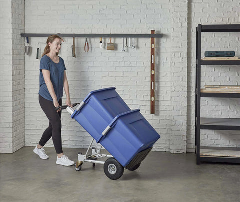 Person using ✝️ COSCO 4-in-1 Folding Series Hand Truck with Flat-Free Wheels carrying a large blue container in a garage.