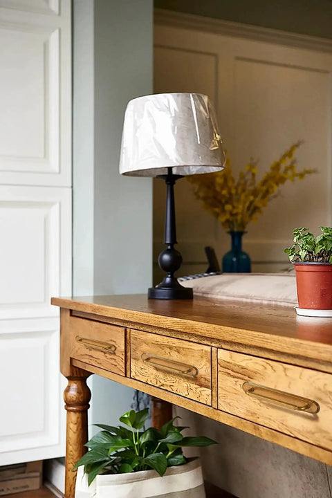 Wooden desk with two pack antique brass cabinet pulls, lamp, and plant