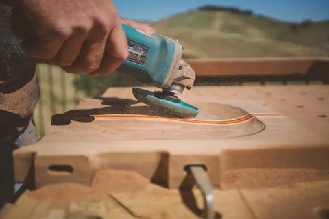Person using Extreme Shaping Disc for Woodworking Coping with Angle Grinder Attachment on wood surface outdoors